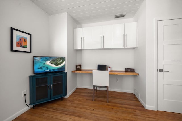 home office with hardwood / wood-style floors, built in desk, and crown molding