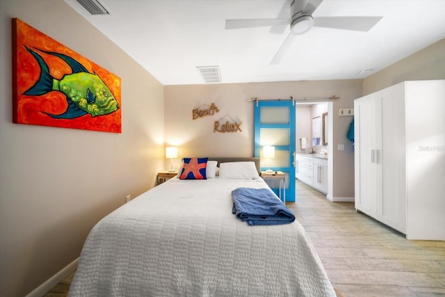 bedroom featuring light wood-type flooring, ensuite bathroom, and ceiling fan