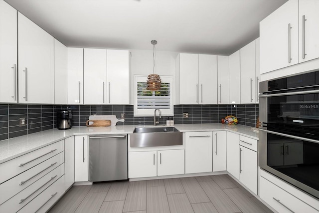 kitchen featuring white cabinets, decorative light fixtures, and stainless steel appliances