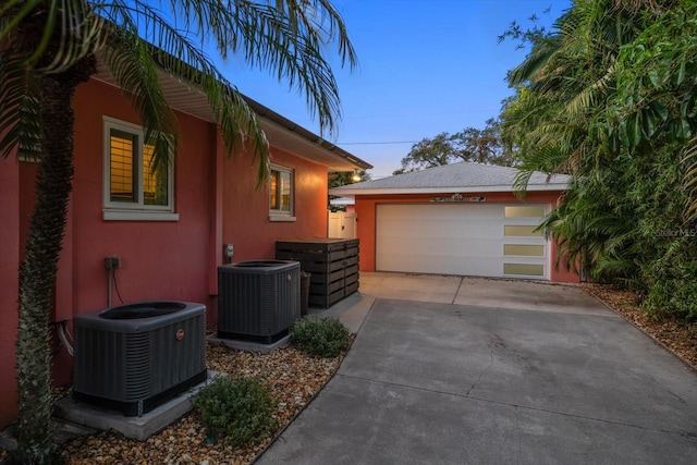 property exterior at dusk featuring central air condition unit, an outbuilding, and a garage