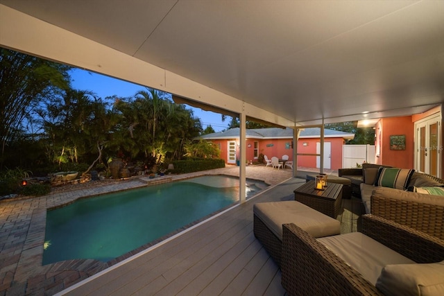 pool at dusk featuring an outdoor living space with a fire pit, an outdoor structure, and a deck