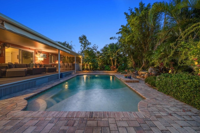 pool at dusk featuring outdoor lounge area and a patio