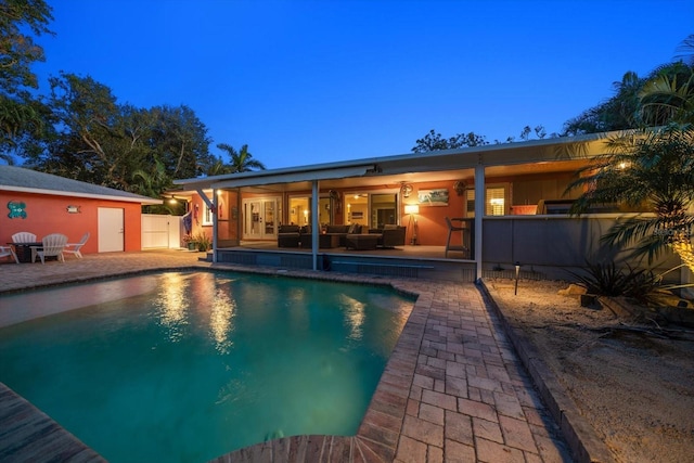 pool at dusk featuring a patio area and an outdoor hangout area