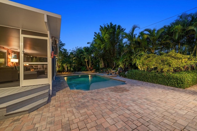 pool at dusk featuring a patio