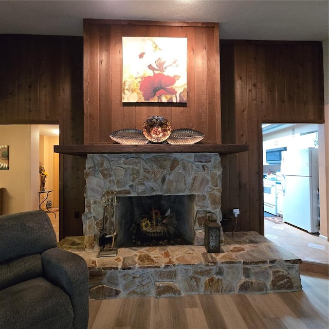 living room featuring a fireplace, hardwood / wood-style floors, and wooden walls