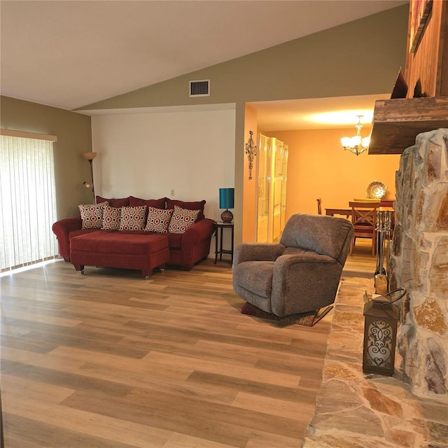 living room with vaulted ceiling, an inviting chandelier, and hardwood / wood-style floors