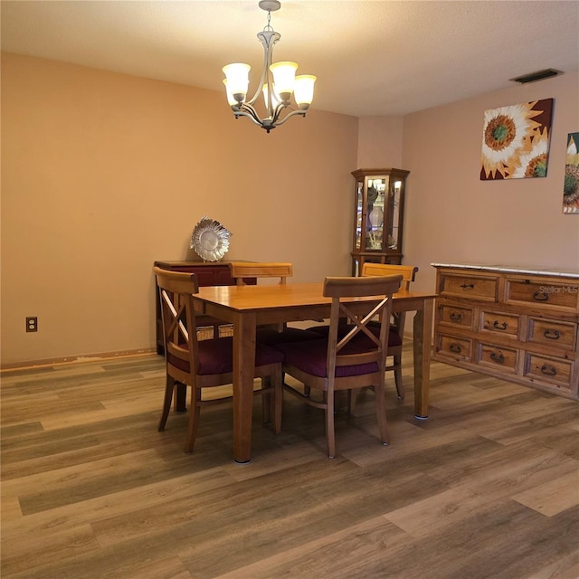 dining space featuring wood-type flooring and a chandelier