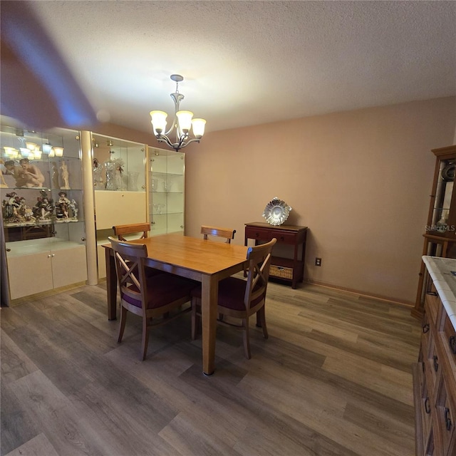 dining space featuring a textured ceiling, dark hardwood / wood-style floors, and an inviting chandelier