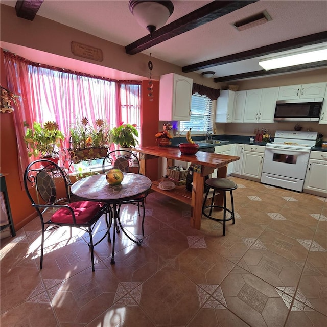 kitchen with white cabinetry, tile patterned flooring, electric range, and beamed ceiling