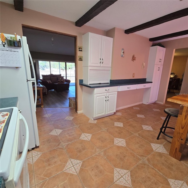 kitchen with built in desk, white cabinets, beamed ceiling, and range