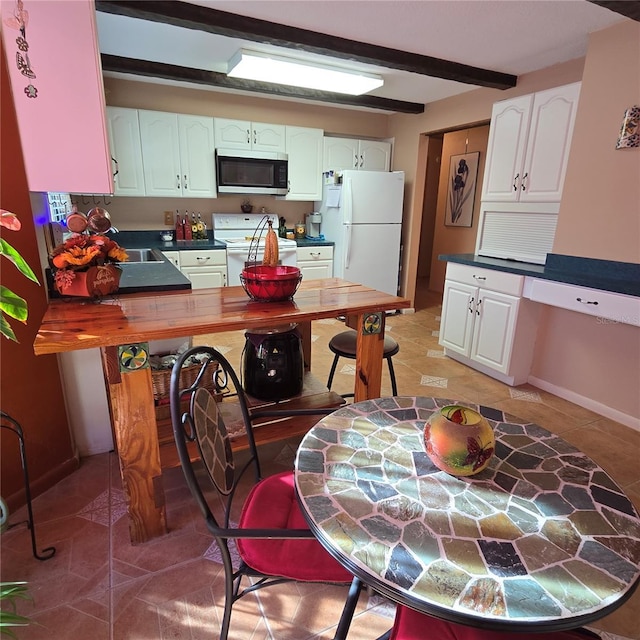 kitchen featuring tile patterned floors, white appliances, white cabinets, and beam ceiling