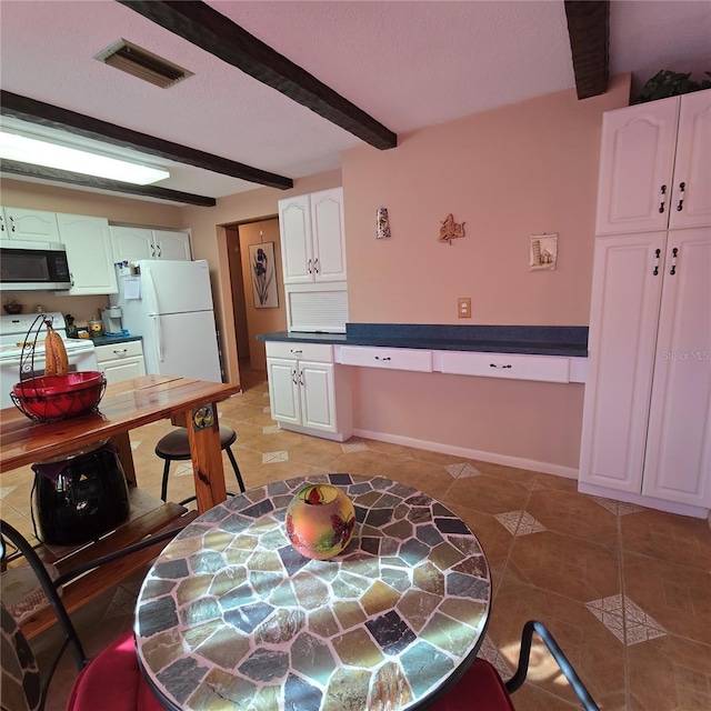 kitchen featuring tile patterned flooring, beam ceiling, white cabinets, and white appliances