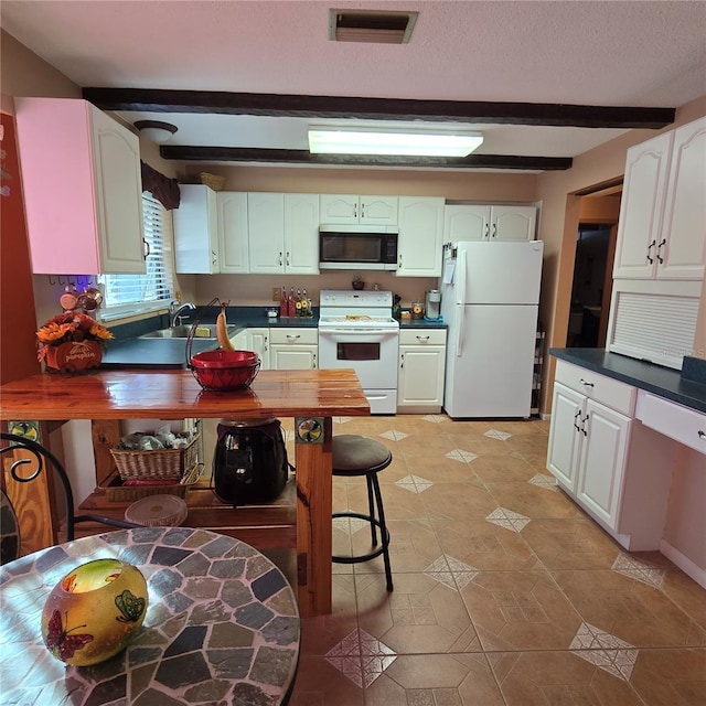 kitchen with white appliances, white cabinets, and beam ceiling