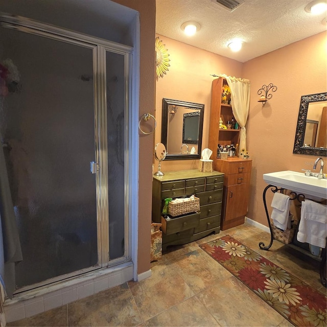 bathroom featuring a textured ceiling and a shower with shower door