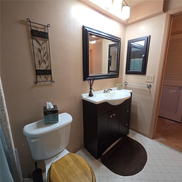 bathroom with toilet, vanity, and tile patterned flooring