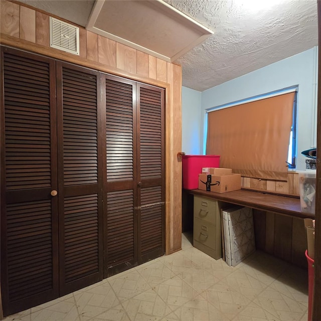 office with wood walls and a textured ceiling