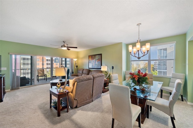 carpeted dining area with ceiling fan with notable chandelier and a textured ceiling