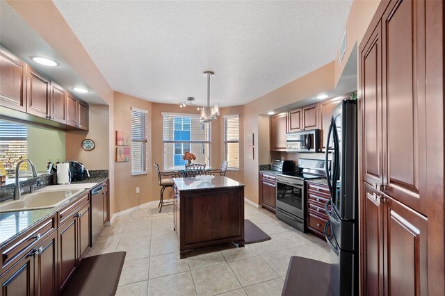 kitchen featuring sink, a center island, an inviting chandelier, a textured ceiling, and appliances with stainless steel finishes