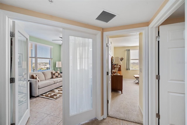 hall with french doors and light colored carpet