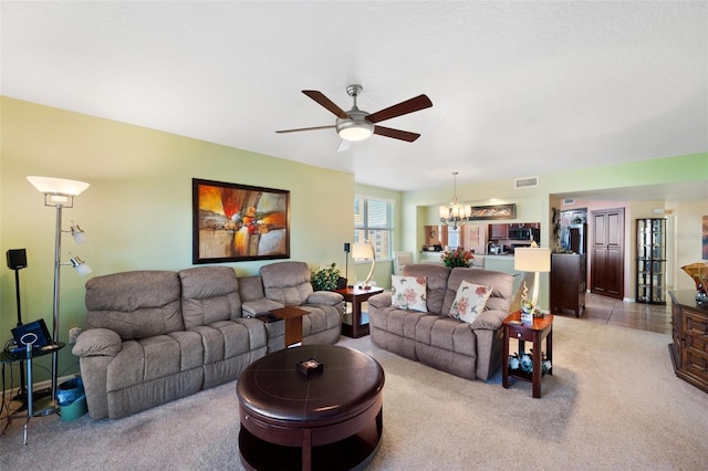 carpeted living room with ceiling fan with notable chandelier