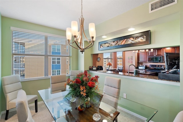 dining space featuring light carpet, a notable chandelier, and sink