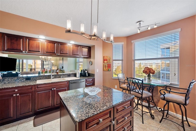 kitchen featuring pendant lighting, stainless steel dishwasher, light tile patterned floors, and a kitchen island