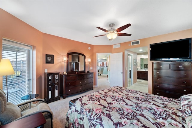 bedroom with light colored carpet, ensuite bath, and ceiling fan