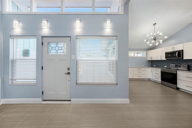 kitchen featuring high vaulted ceiling, plenty of natural light, white cabinetry, and appliances with stainless steel finishes