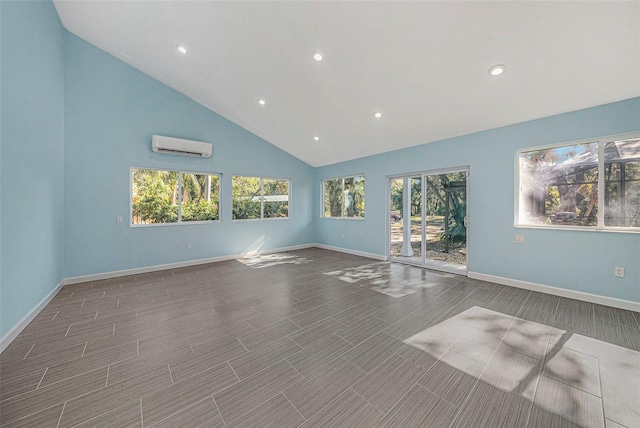 empty room featuring hardwood / wood-style floors, high vaulted ceiling, and a wall mounted air conditioner