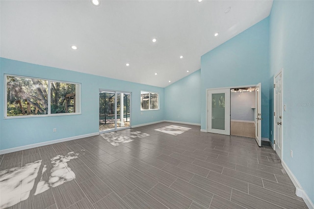 unfurnished living room featuring french doors and high vaulted ceiling