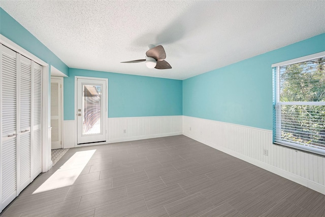 unfurnished bedroom with ceiling fan, a textured ceiling, and multiple windows