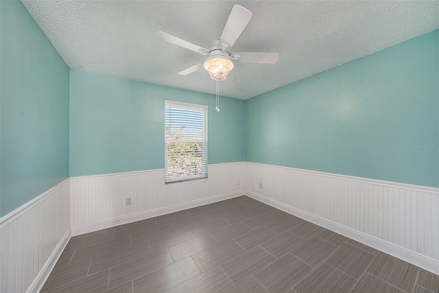 unfurnished room with a textured ceiling, ceiling fan, and dark wood-type flooring