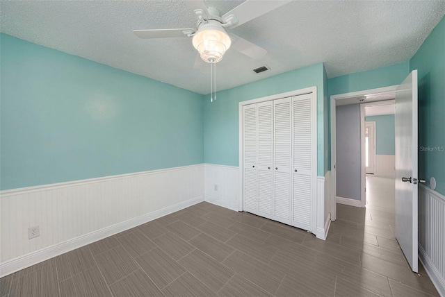 unfurnished bedroom with ceiling fan, a closet, and a textured ceiling