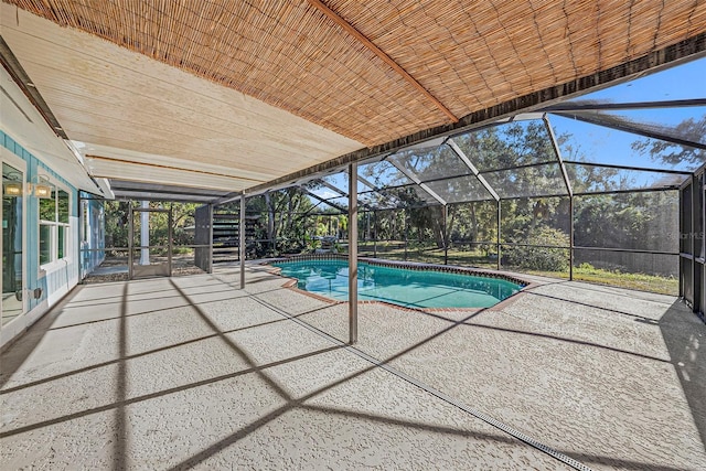 view of pool with glass enclosure and a patio area