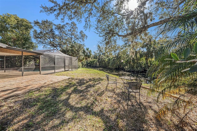 view of yard with glass enclosure, a patio, and a swimming pool