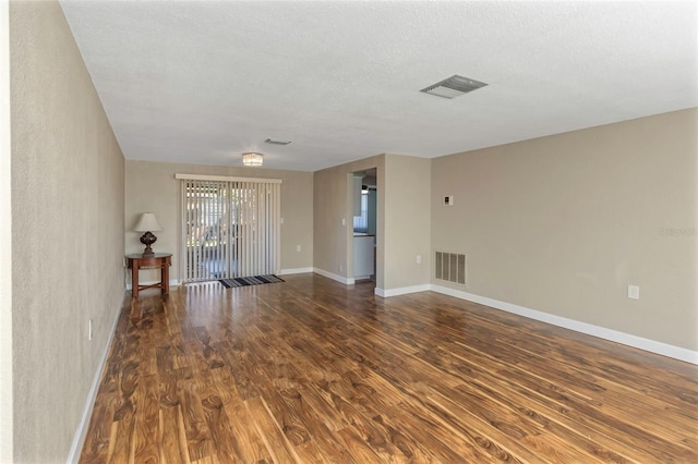 unfurnished room with dark wood-type flooring and a textured ceiling