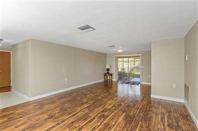 spare room featuring light wood-type flooring and a textured ceiling