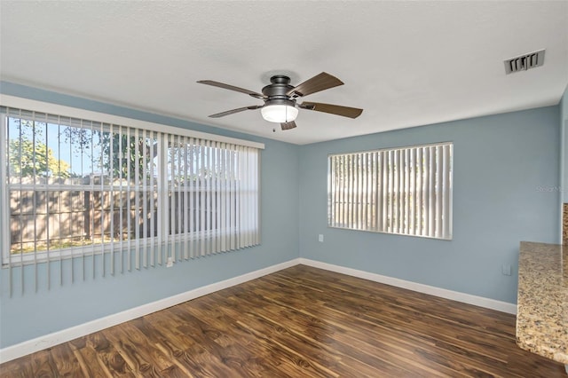 unfurnished room featuring dark hardwood / wood-style floors, ceiling fan, a textured ceiling, and a wealth of natural light