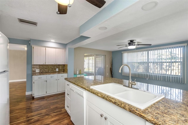 kitchen with light stone counters, a textured ceiling, white appliances, dark wood-type flooring, and sink