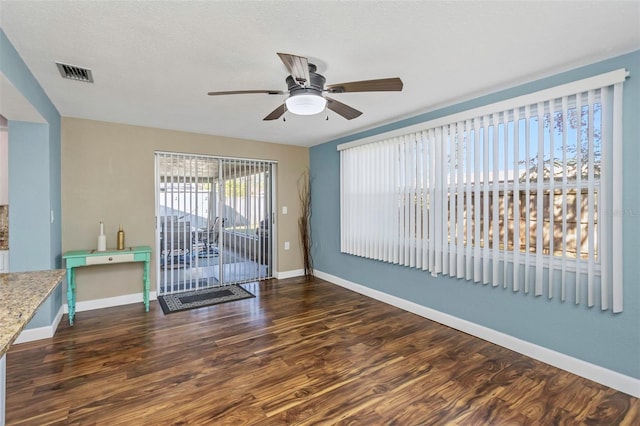 empty room featuring dark hardwood / wood-style floors, ceiling fan, and a textured ceiling