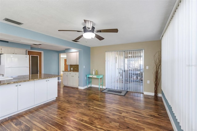 kitchen with dark hardwood / wood-style floors, white fridge, white cabinetry, and stone counters