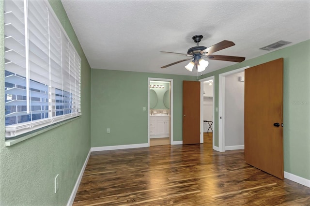 unfurnished bedroom featuring a textured ceiling, ceiling fan, dark wood-type flooring, and connected bathroom