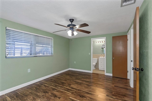 unfurnished bedroom with a textured ceiling, dark hardwood / wood-style floors, ceiling fan, and ensuite bathroom