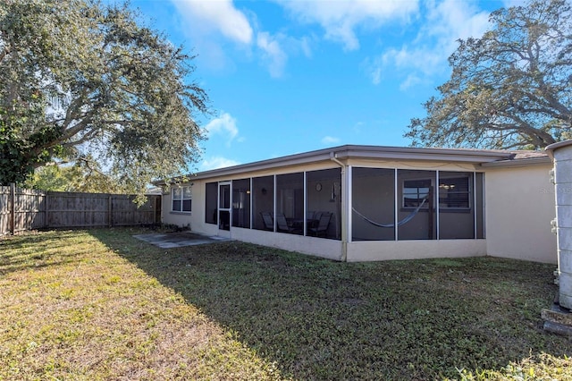 back of house featuring a lawn and a sunroom