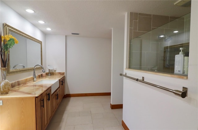 bathroom with tile patterned floors, vanity, an enclosed shower, and a textured ceiling