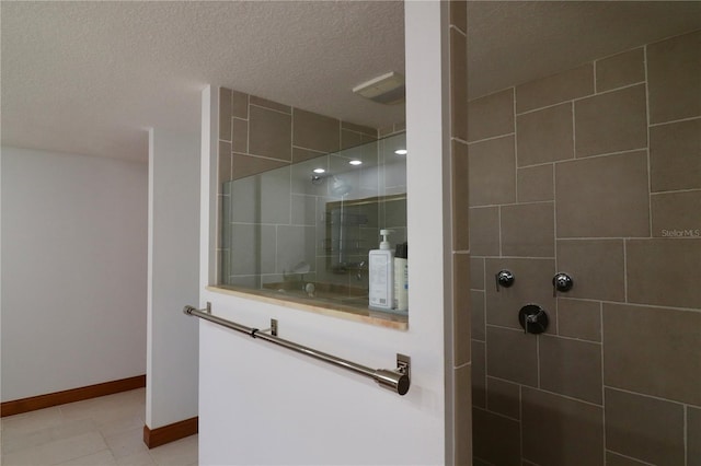 bathroom featuring tile patterned flooring, a tile shower, and a textured ceiling