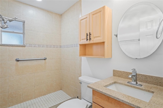 bathroom featuring a tile shower, vanity, and toilet