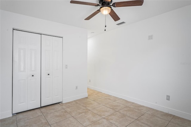 unfurnished bedroom featuring light tile patterned floors, a closet, and ceiling fan