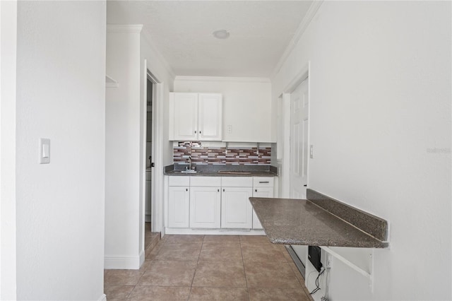 kitchen with decorative backsplash, ornamental molding, sink, light tile patterned floors, and white cabinetry