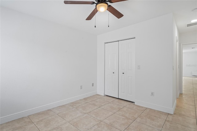 unfurnished bedroom with ceiling fan, light tile patterned floors, and a closet